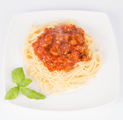 Spaghetti bolognese decorated with basil on a white background