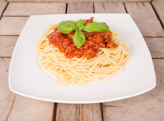 Spaghetti bolognese decorated with basil being eaten with a fork