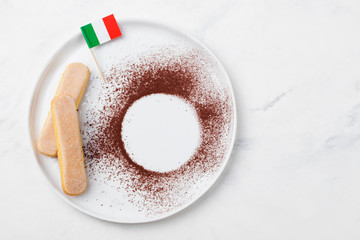 Ingredients for tiramisu dessert with Italian flag on a white plate, savoiardi cookies, cocoa powder