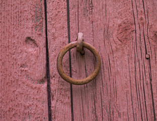 Horse Tie Off Ring: An old iron ring used to tie a horse to on the side of an red barn