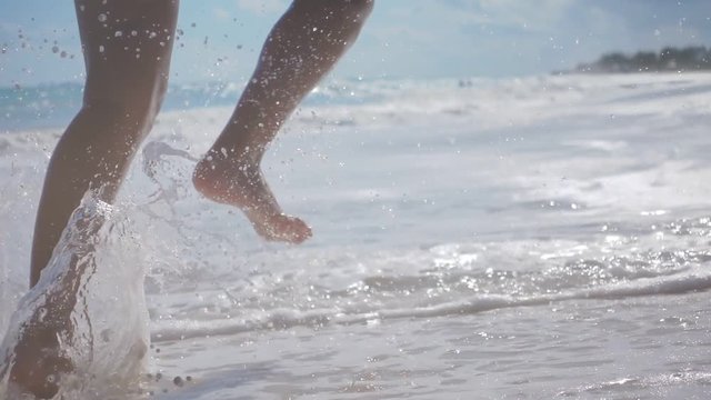 extreme slow motion of female legs running splashing into water