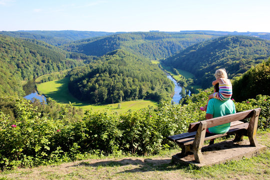 Father and child hiking and enjoying view from famous panoramic point of The Giant's tomb of the river Semois, located nearby the city of Bouillon, Wallonia, Ardennes, Belgium.