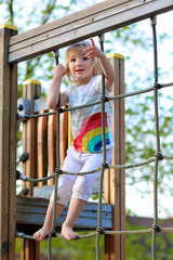 Obraz premium Little girl having fun at playground. Happy cute child, blond sportive toddler girl in casual outfit, playing in the park on a sunny day. Leisure outdoors activity with children.