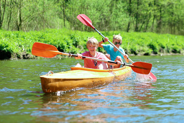 Two boys kayaking on the river. Active happy friends, teenage schoolboys, having fun together enjoying adventurous experience with kayak on a sunny day during summer vacation