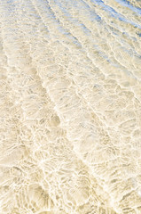 Barfuß durch seichtes kristallklares Meerwasser laufen, auf weichem weißem Sand, sanfte...