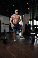 Fototapeta na wymiar Man In The Gym Exercising Back With Barbell