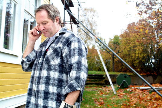Man talking in mobile phone behind house