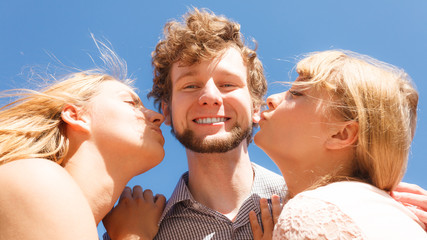 Two girls kissing one boy having fun outdoor