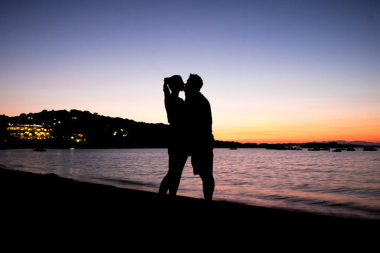 Silhouette of two lovers who kiss and hug