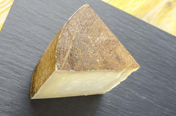 Piece of sheep milk cheese over slate plate