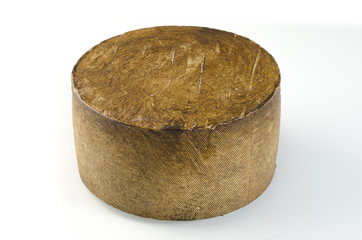 Whole wheel of sheep milk cheese over white background.