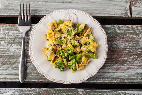 Scrambled eggs with broccoli, onions, and green bell peppers top view on a weathered old barn wood table