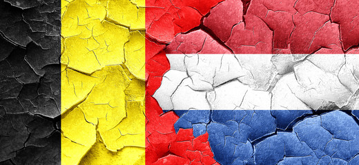 Belgium flag with Netherlands flag on a grunge cracked wall