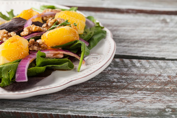 Walnut orange spinach vinaigrette salad on a weathered old barn wood table side view