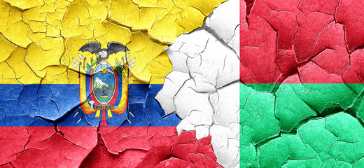 Ecuador flag with Madagascar flag on a grunge cracked wall