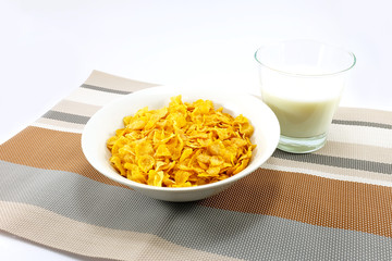 cornflakes with a cup of milk on colorful table mat
