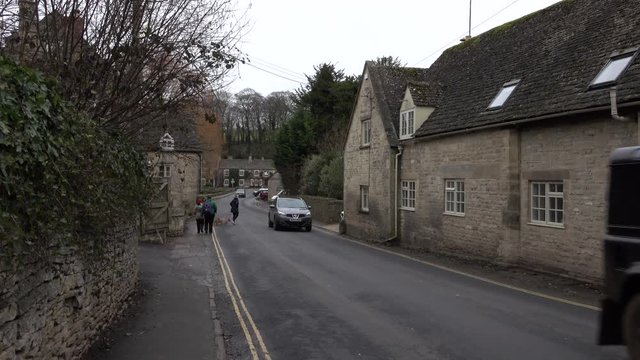 Bibury Cotswolds England traffic narrow old road. Historical village with homes businesses. Cotswolds, Area of Outstanding Natural Beauty (AONB) rolling hills and rivers. Destination for tourism