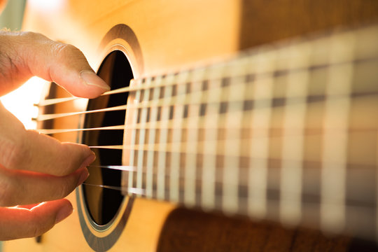 Man's hands playing acoustic guitar.