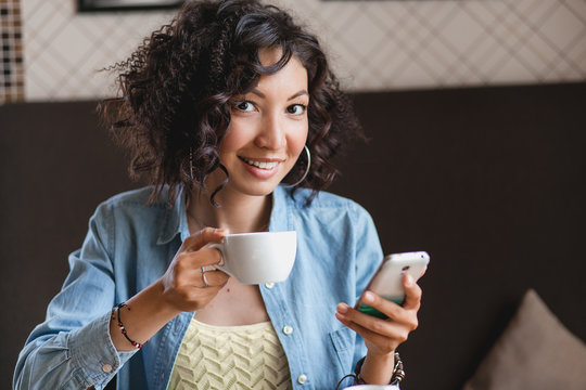 the curly woman in cafe with coffee and smart phone. The