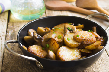 Fried potatoes with mushrooms in a frying pan