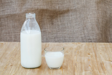 Bottle of fresh milk and one glass on wooden table