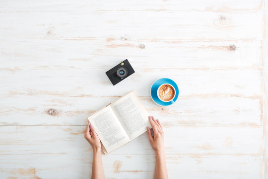 Female Hands Holding Book On The Wooden Desk