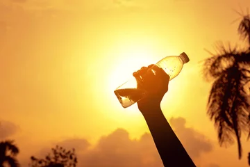 Gordijnen Silhouette handle water bottle with sunset background © Songwut Pinyo