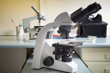 Professional microscope close-up with chemist scientific researcher hands using microscope in the laboratory interior.