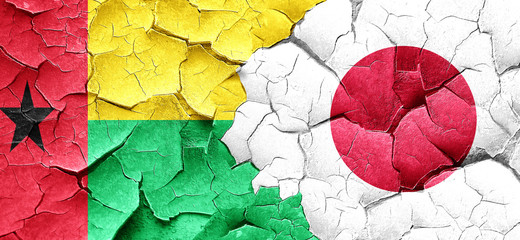 Guinea bissau flag with Japan flag on a grunge cracked wall