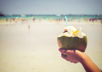 Fresh coconut cocktails with in woman hands on tropical beach - vacation in summer. vintage color styles