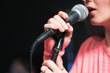 Microphone and unrecognizable female singer close up. Cropped image of female singer in pink dress...