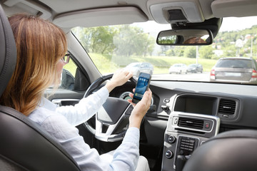 Dangerous driver. Woman using handy in her car while driving