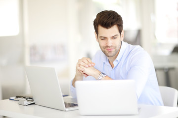 Solve the problem. Young businessman working on solving the problem on laptop at office.