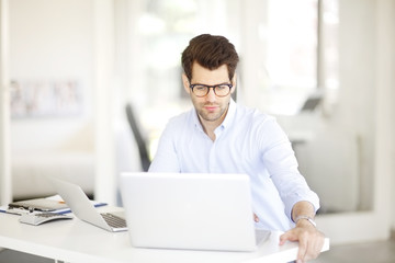Solve the problem. Young businessman working on solving the problem on laptop at office.