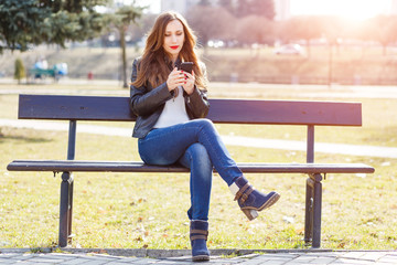 Young smiling woman using smartphone in park