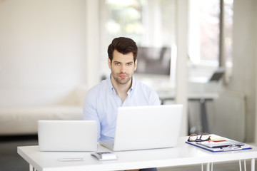 Solve the problem. Young businessman working on solving the problem on laptop at office.