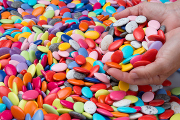 Hands of woman holding colorful chocolate drops. Close-up.