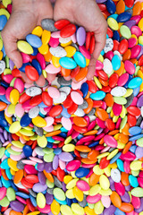 Hands of woman holding colorful chocolate drops. Close-up.