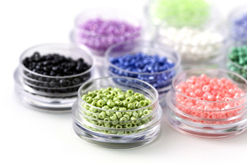 Small colorful beads on transparent round boxes on white background