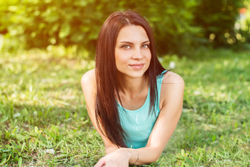 Beautiful woman relaxing outdoors on grass looking happy and smiling.