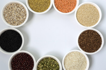 Different kinds of groats in small white bowls on white background