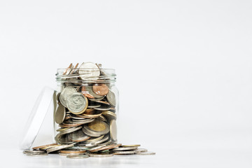 Glass jar full of coins, with copy space on white background