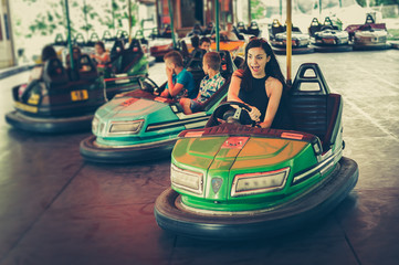 Cute young woman having fun in electric bumper car in amusement park - obrazy, fototapety, plakaty