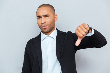 Young guy showing thumbs down sign over gray background