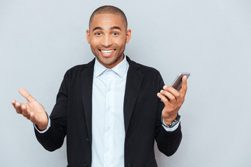 Smiling young man with smart phone over grey background