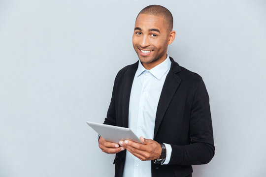 Happy african american young man smiling and using tablet