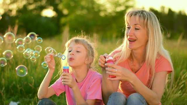 Mother and the child blowing bubbles. Slow motion
