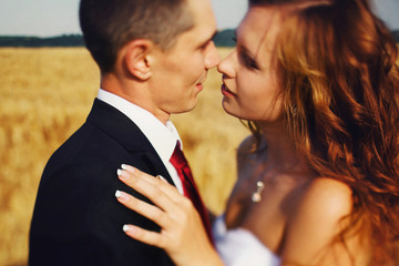 Bride reaches to kiss a fiance while wind blows her hair