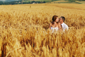 A view on the groom and bride having fun among the wheat