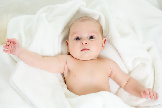 Cute baby lying on back in bathing towel